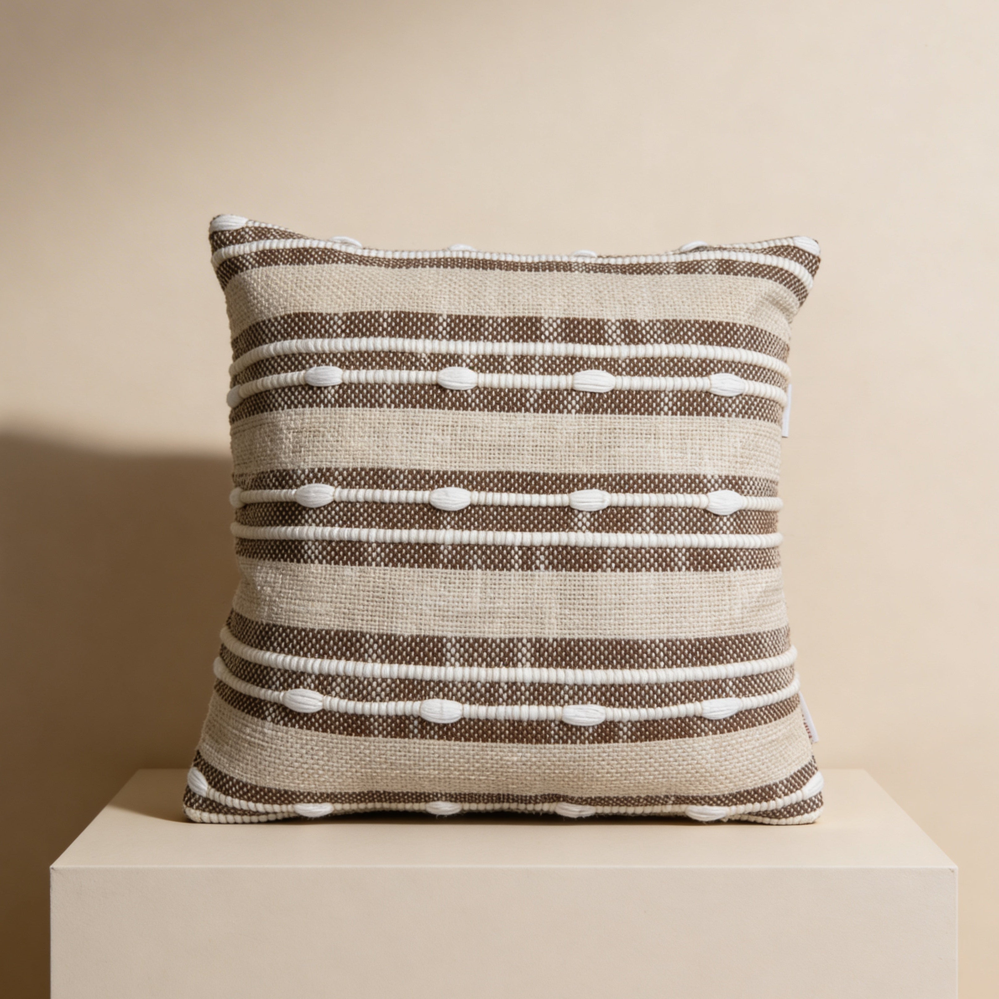 Striped pillow on a white pedestal against a beige background