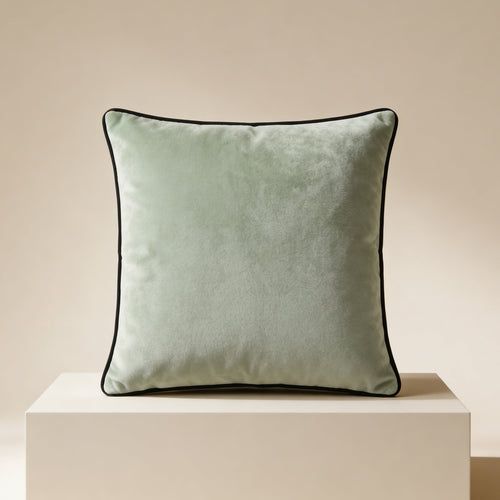 Green cushion with a black border on a beige pedestal against a beige background